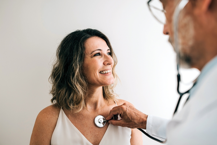 A doctor listens to a woman's heart with a stethescope