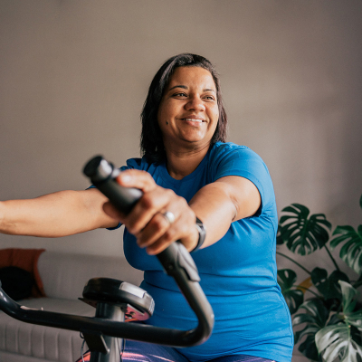 A woman sitting on a workout machine, smiling