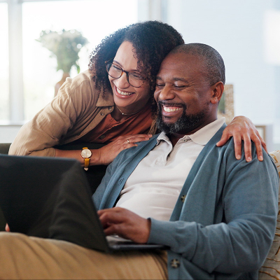 A man and woman smiling at a laptop screen