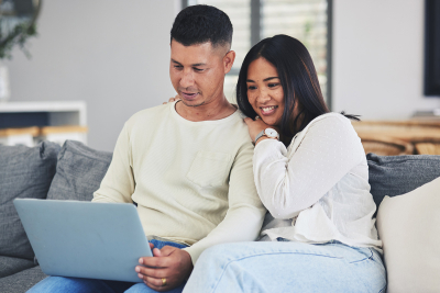 A man and woman smiling at a laptop screen