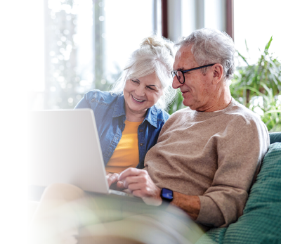 Man and woman sitting in the couch in front of a laptop
