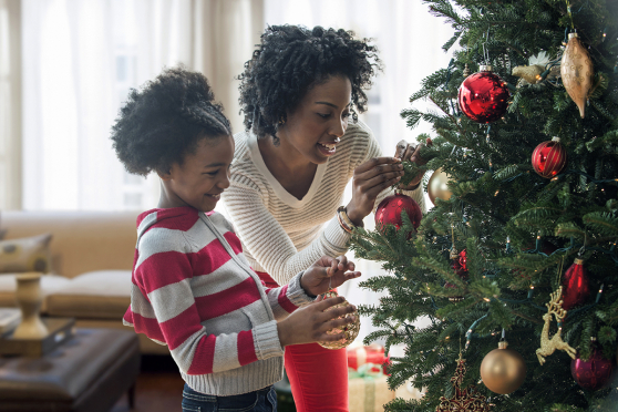 Mother and daughter hanging ornaments on a Christmas tree.