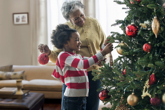 Grandmother and grandchild hanging ornaments on a Christmas tree.