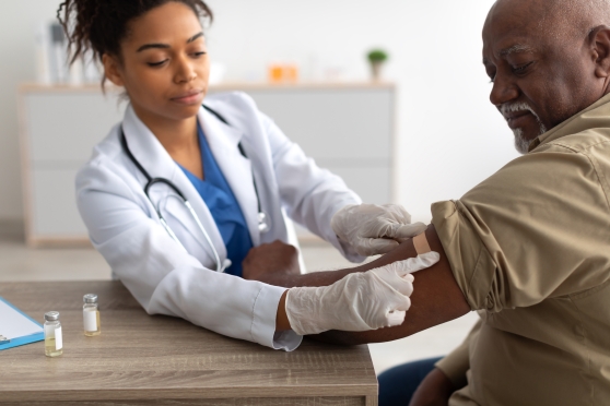 A female doctor bandages a man's arm after he received a vaccination.