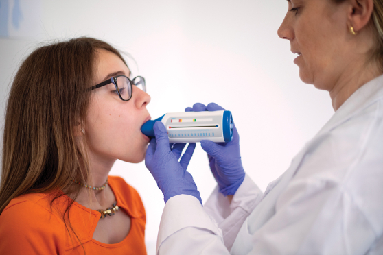 A little girl uses a peak flow meter
