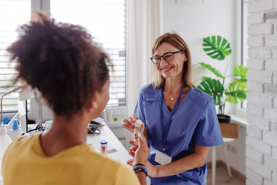 Woman giving urine sample to doctor